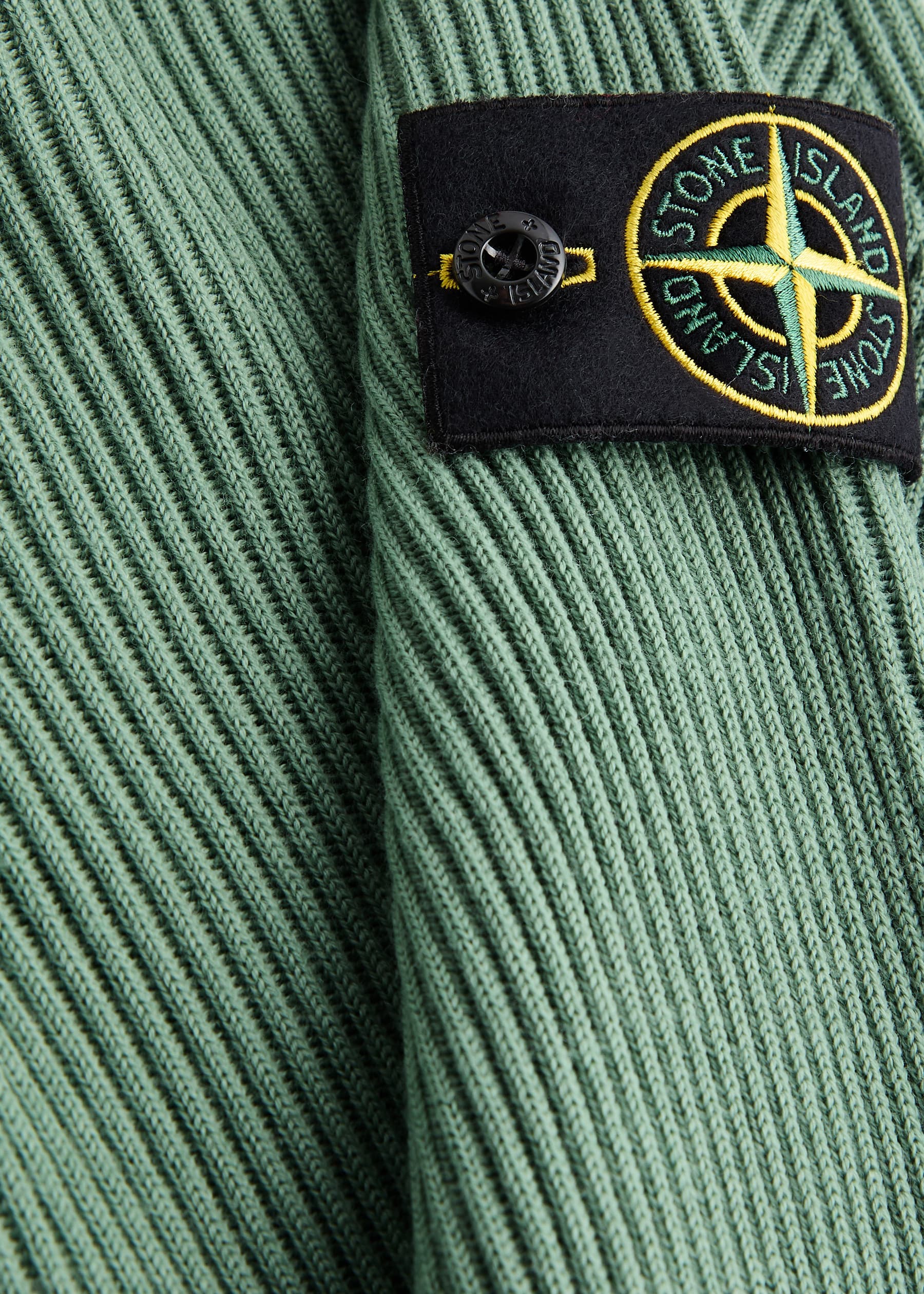 Close-up of a Stone Island badge against ribbed knit fabric