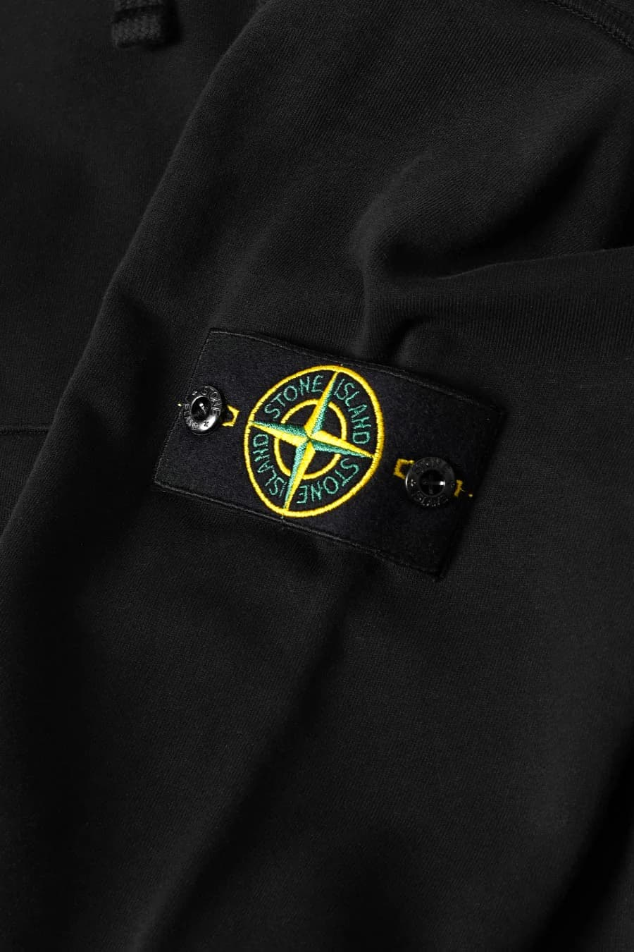 Stone Island badge attached to a black sleeve